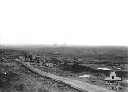 Image of A view from the duckboards, near the 'Cough Drop', in front of High Wood, looking east, showing German shells bursting behind the former Australian positions, near Flers.